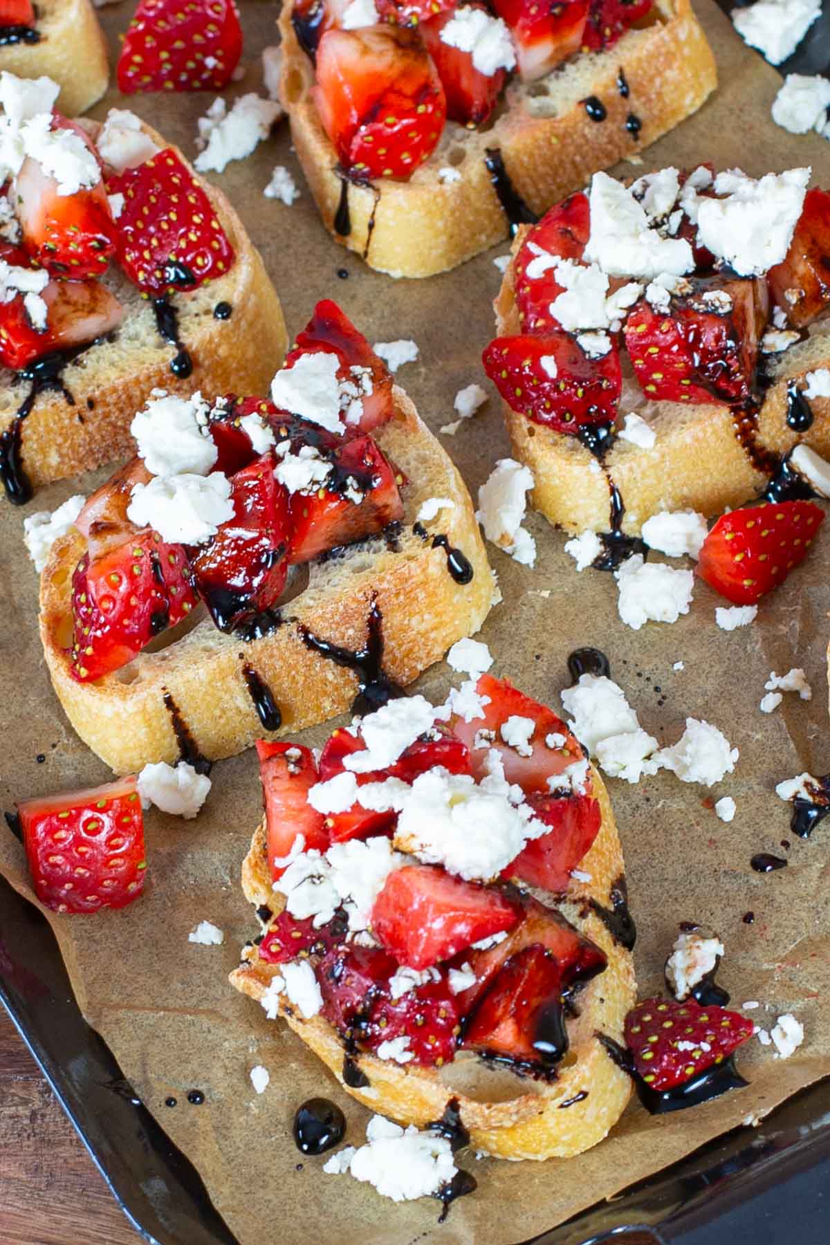 Slices of baguette topped with strawberries, feta cheese drizzled with balsamic glaze.