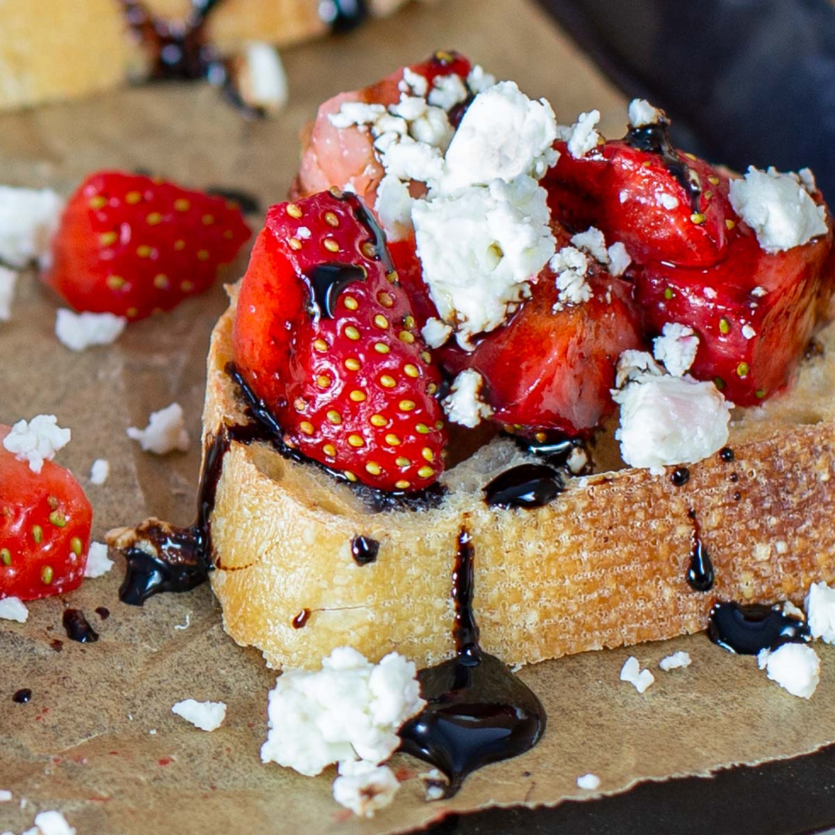 Slices of baguette topped with strawberries, feta cheese drizzled with balsamic glaze.