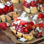 Slices of baguette topped with strawberries, feta cheese drizzled with balsamic glaze.