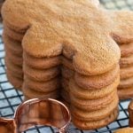 Stack of gingerbread men cookies on cooling rack with copper cookie cutter.