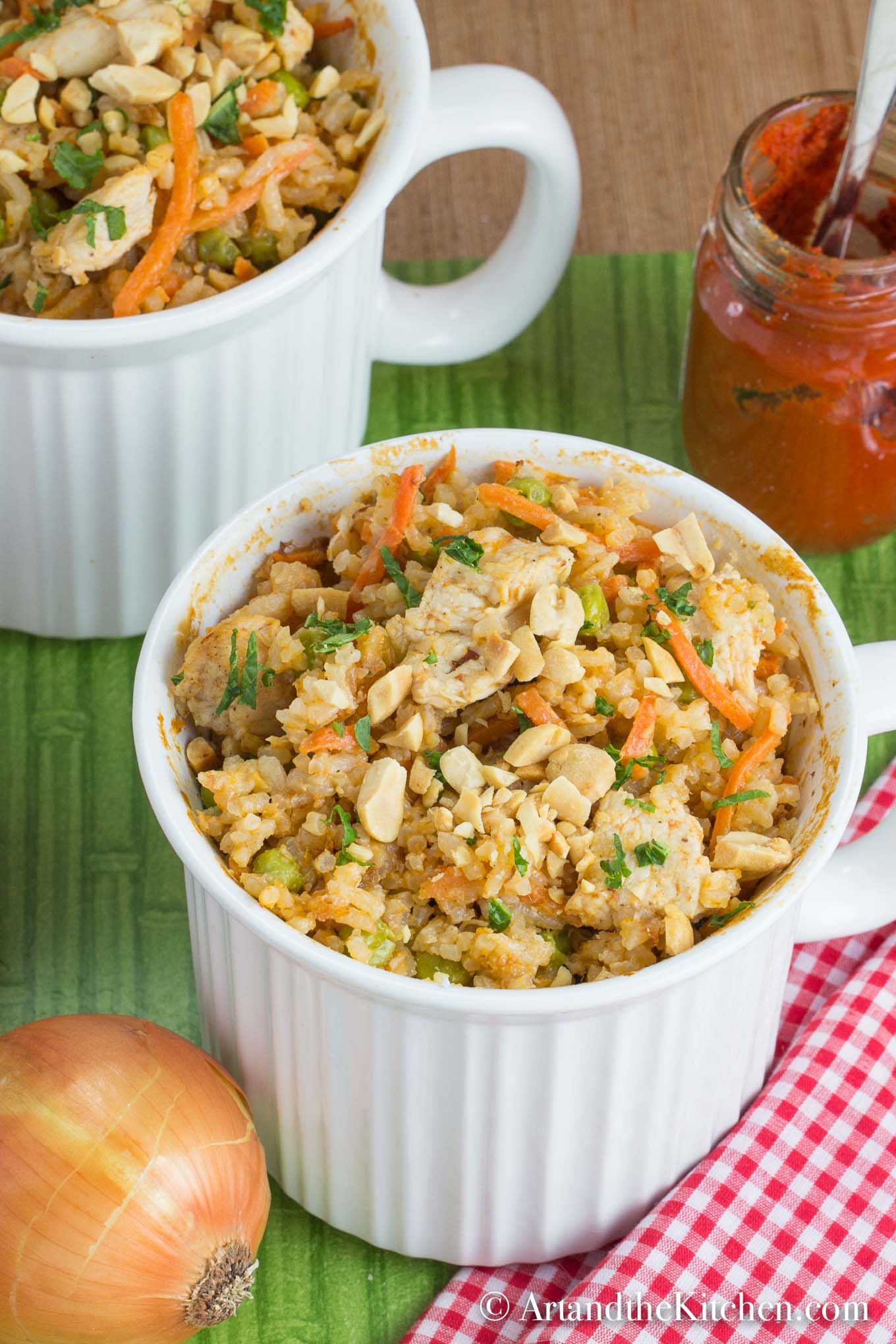 White mug bowls of chicken curry topped with chopped peanuts.