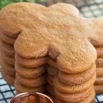 Stack of gingerbread men cookies on cooling rack with copper cookie cutter.
