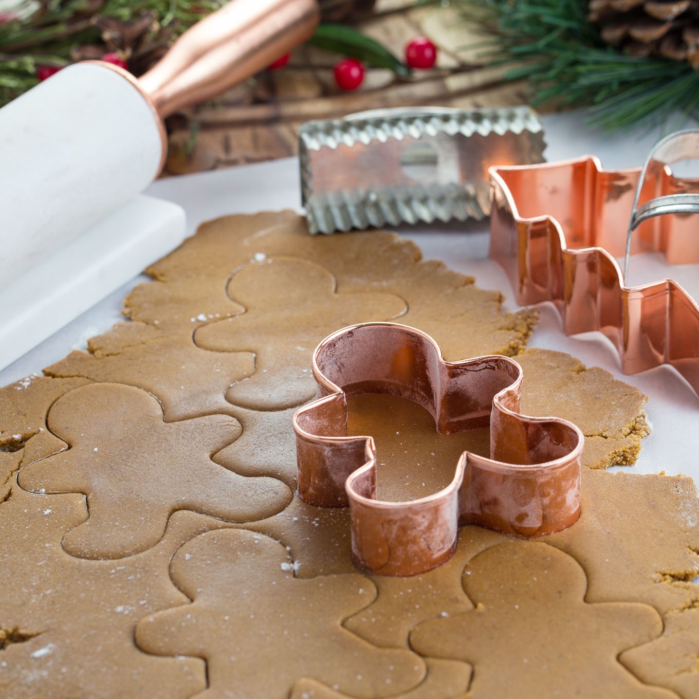 Rolled out gingerbread dough with copper cookie cutter cutting out shapes.