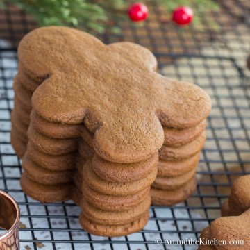 Stack of gingerbread men cookies on cooling rack with copper cookie cutter.