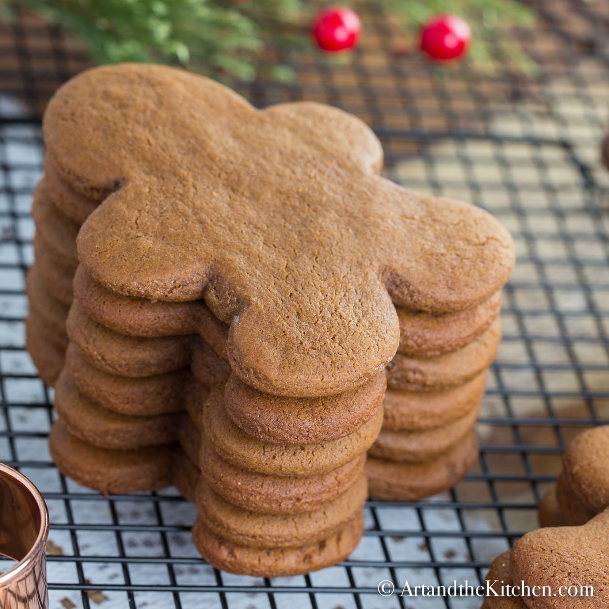 Stack of gingerbread men cookies on cooling rack with copper cookie cutter.