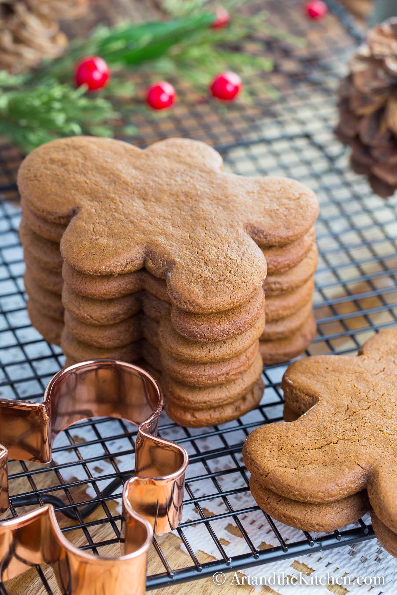 Stack of gingerbread men cookies on cooling rack with copper cookie cutter.