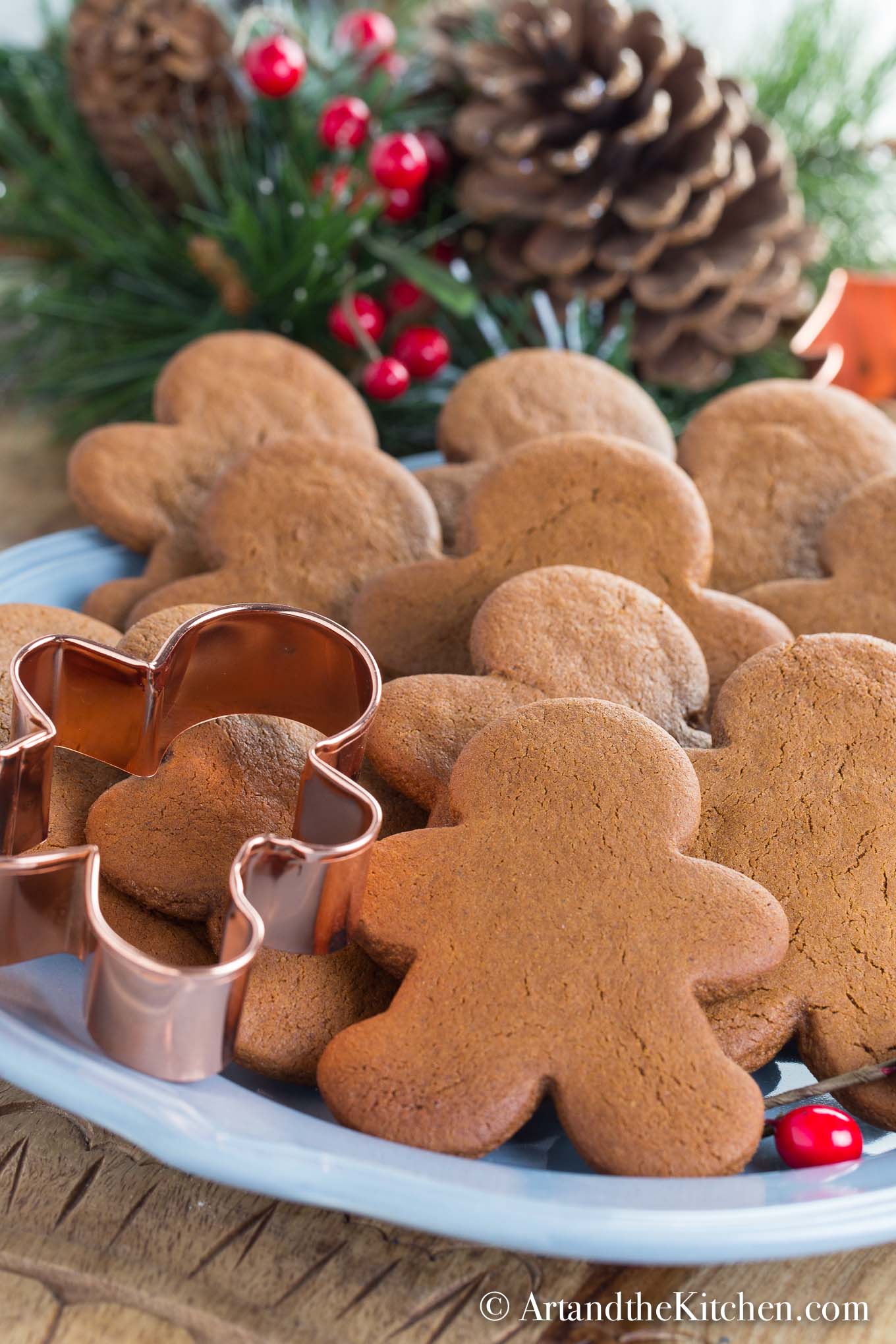 Plate filled with undecorated gingerbread men and copper gingerbread man cookie cutter.