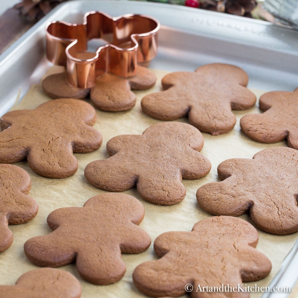 Baked gingerbread men cookies on brown parchment lined baking sheet.