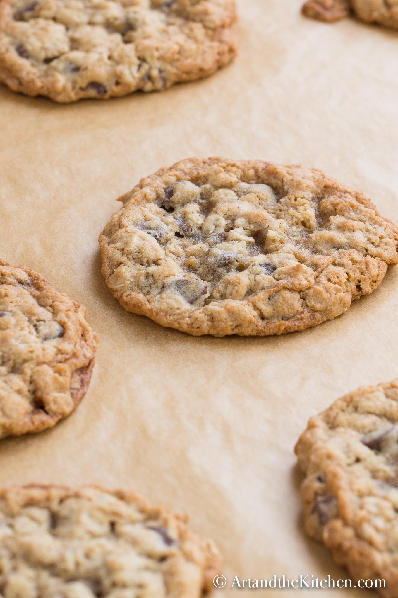 Brown parchment lined baking pan filled with baked chocolate chip cookies.