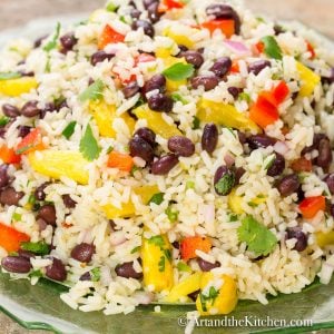 Colorful salad with coconut rice, black bean, pineapple, red peppers, onion, and cilantro on a green plate.