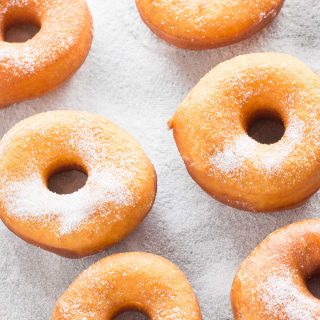 baking pan with fresh cooked donuts sprinkled with white sugar