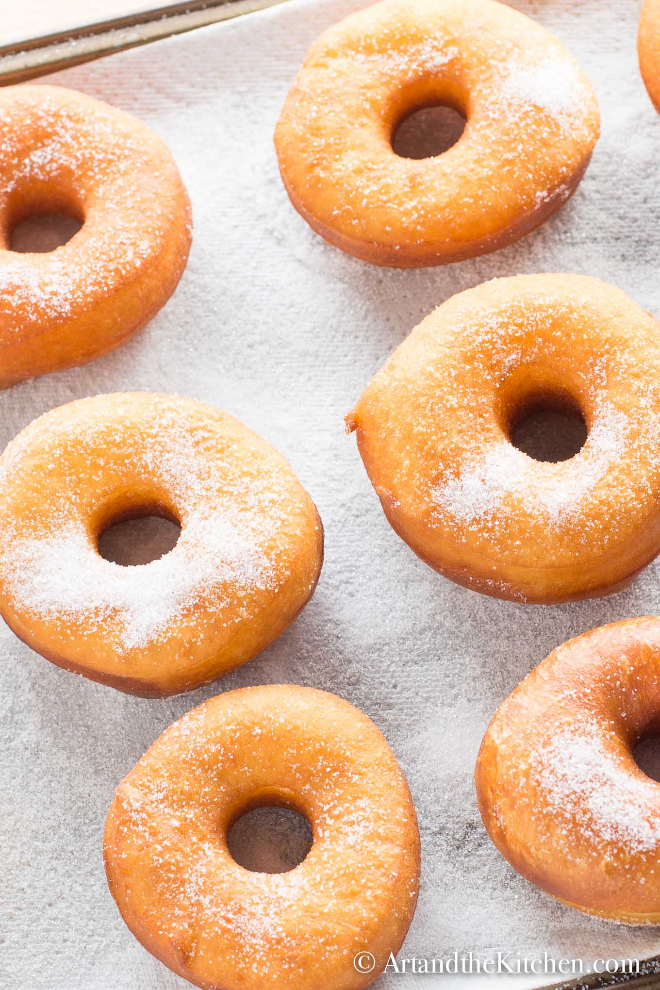 Freshly baked donuts sprinkled with sugar on white napkin.