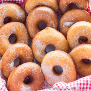 rows of freshly baked homemade donuts sprinkled with sugar in a basket