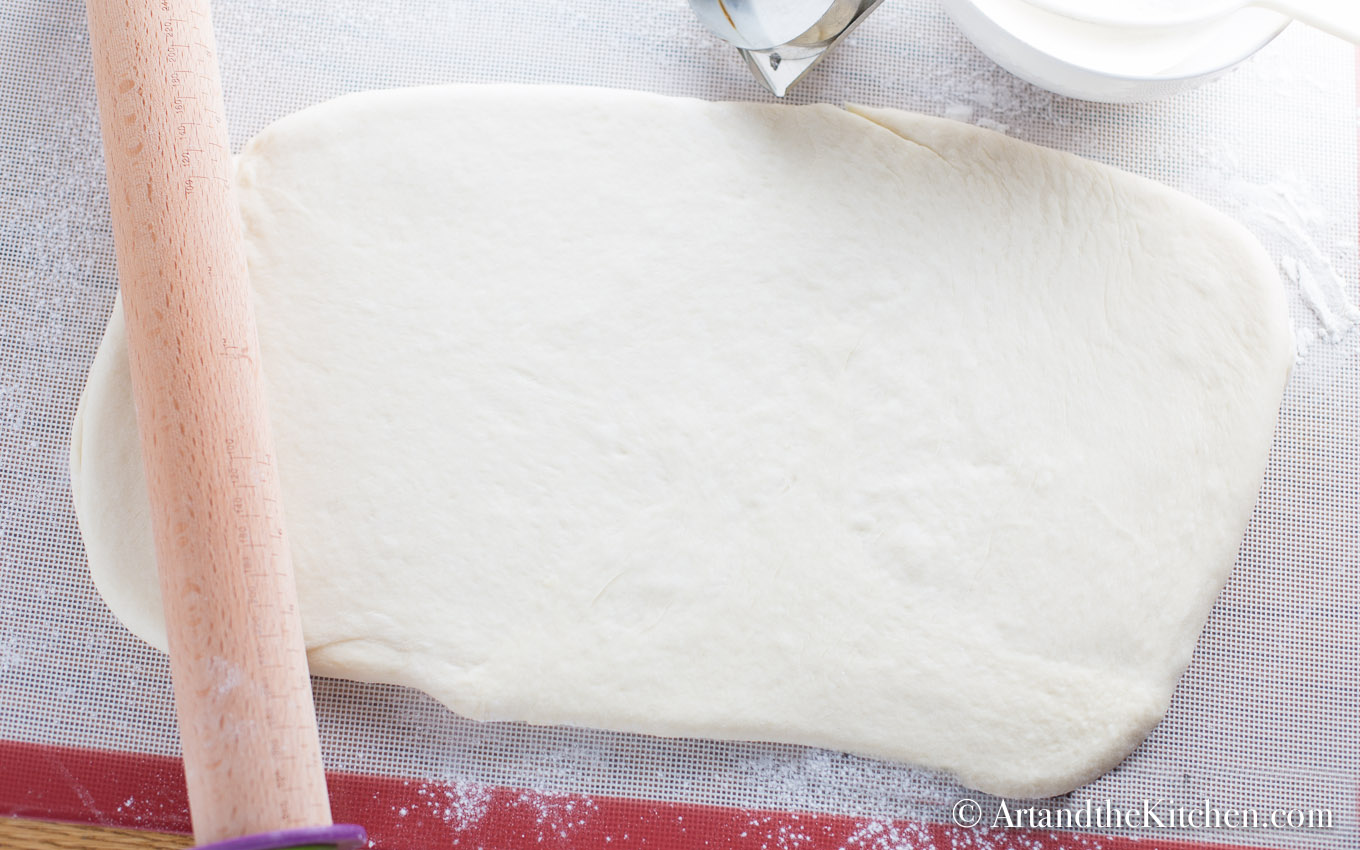 Dough rolled out on floured surface with rolling pin.