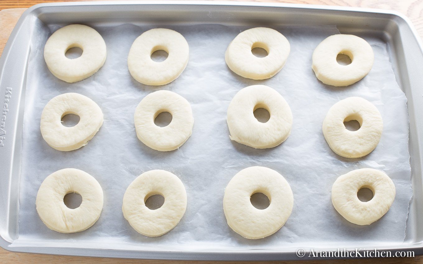 Bread machine donuts ready for frying on parchment lined baking sheet.