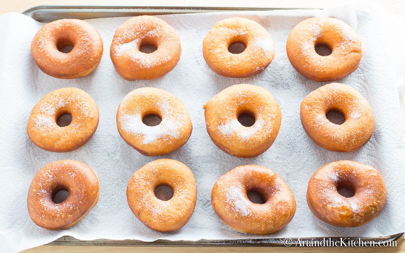 Baking tray filled with fresh fried donuts.