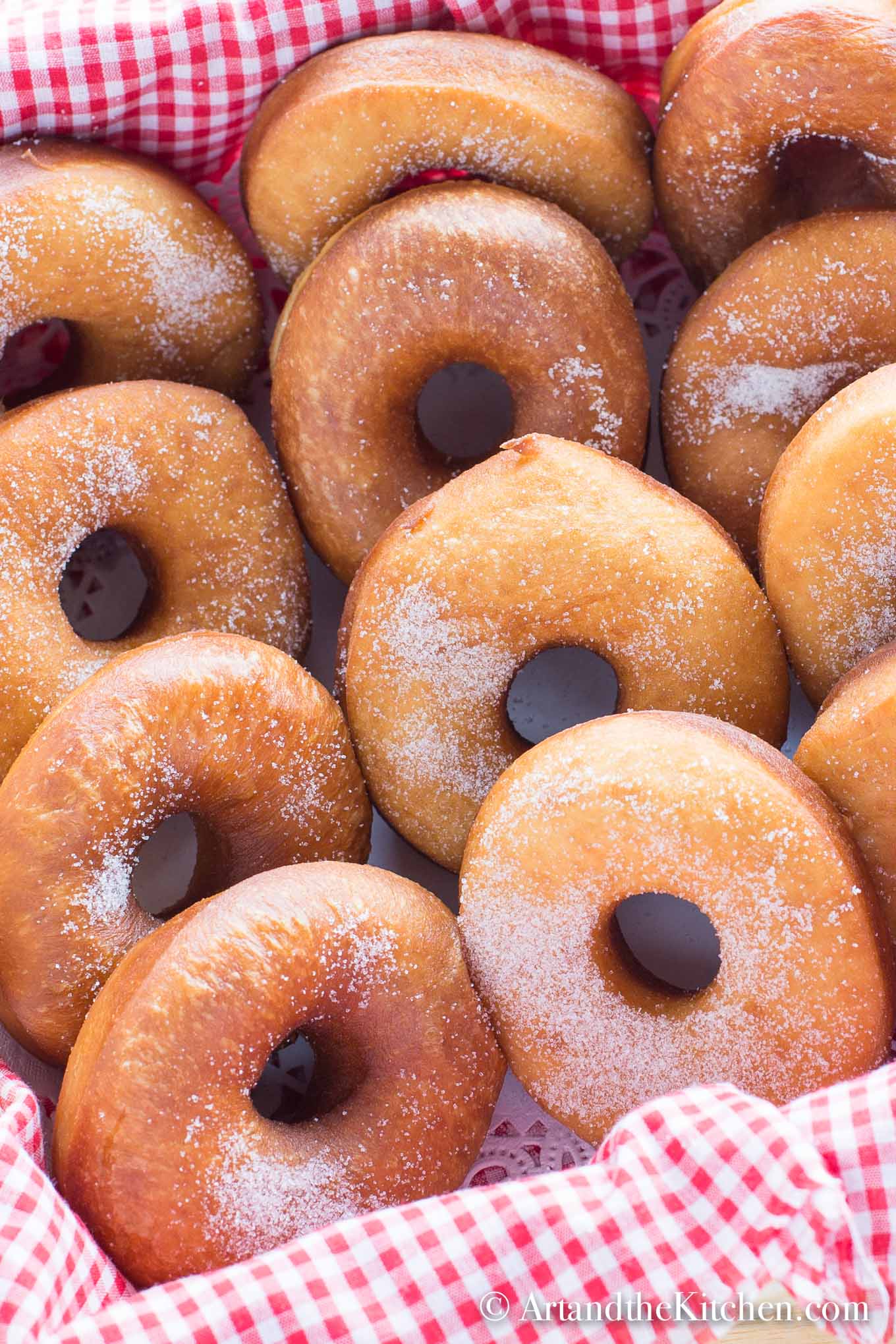 Rows of homemade plain donuts sprinkled with sugar.