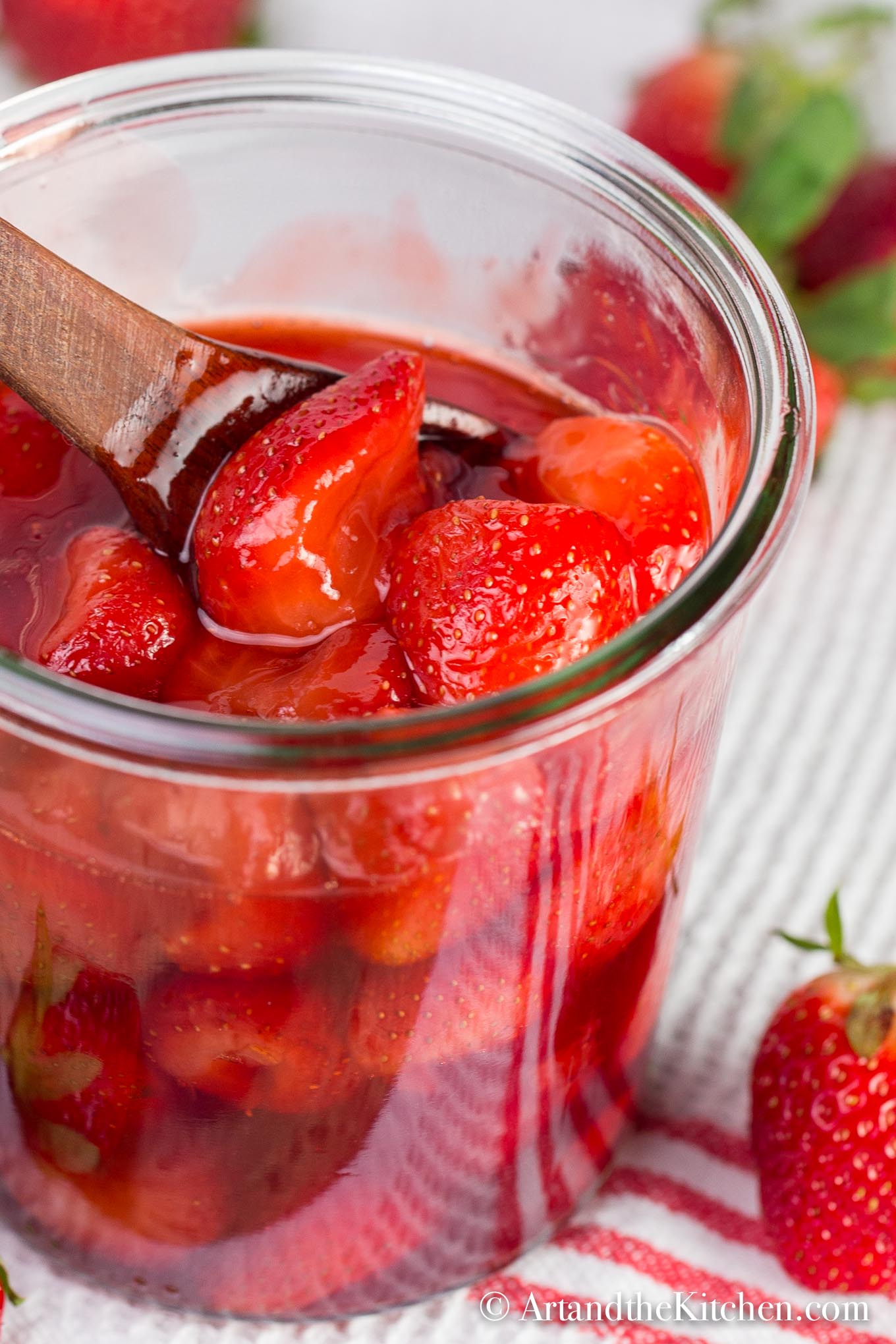 strawberry sauce in glass jar with wooden spoon.