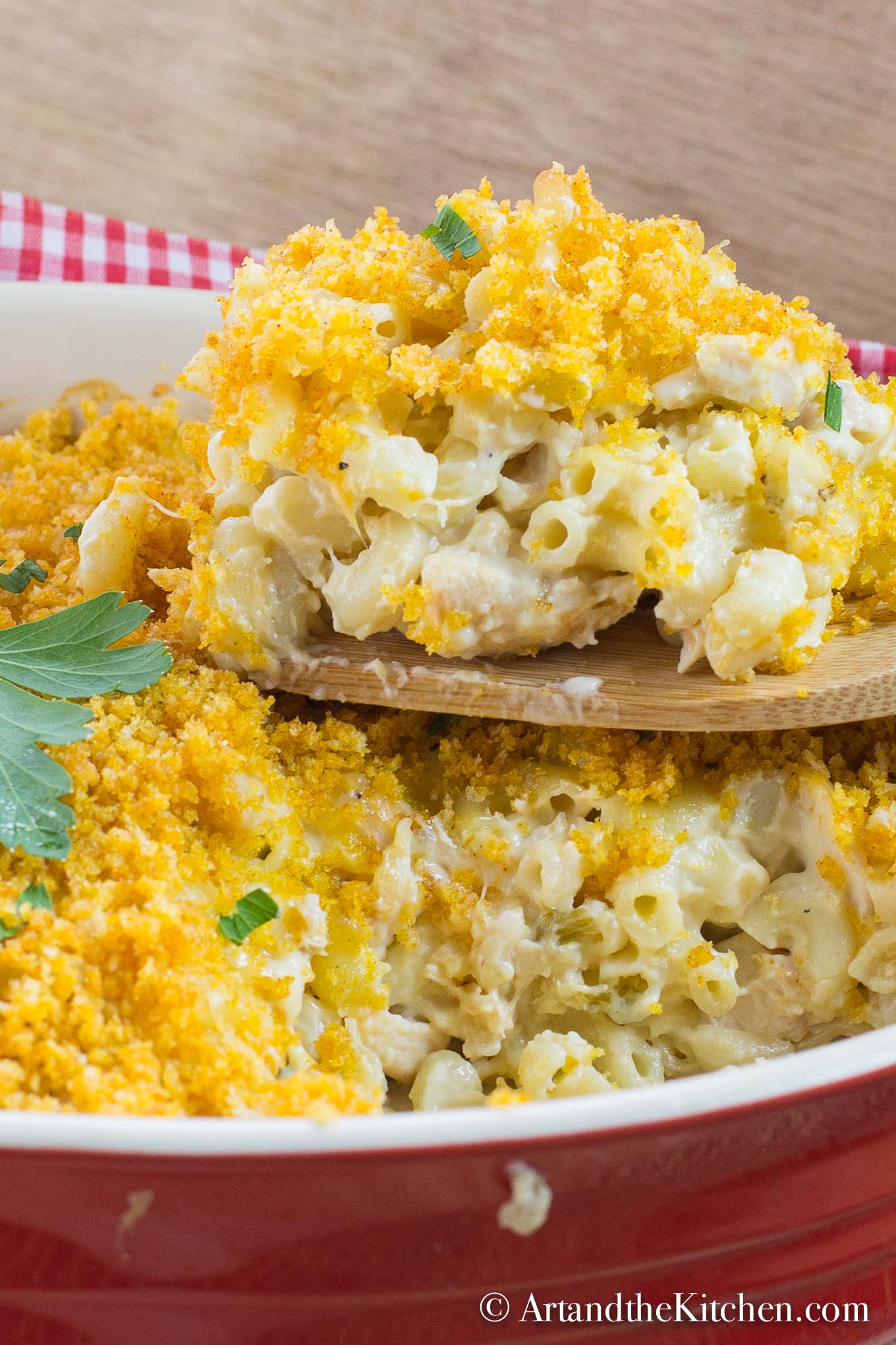 Macaroni casserole with cubes of chicken, golden brown panko bread crumb topping. Served in red stoneware baking dish.