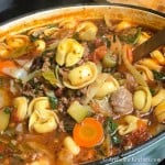 Dutch oven filled with soup of tortellini, vegetables, sausage and ground beef.