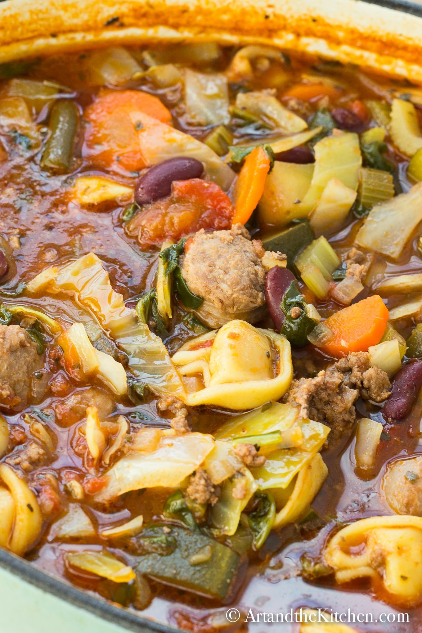 Dutch oven filled with soup of tortellini, vegetables, sausage and ground beef.