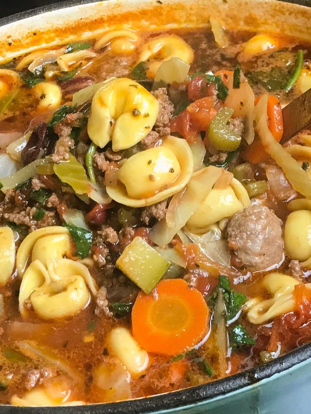Dutch oven filled with soup of tortellini, vegetables, sausage and ground beef.