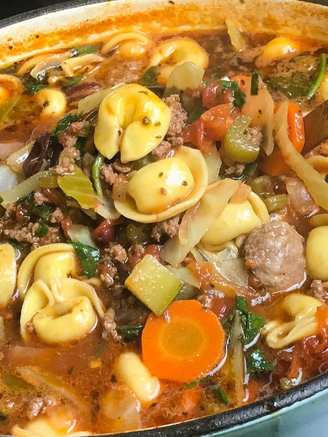Dutch oven filled with soup of tortellini, vegetables, sausage and ground beef.