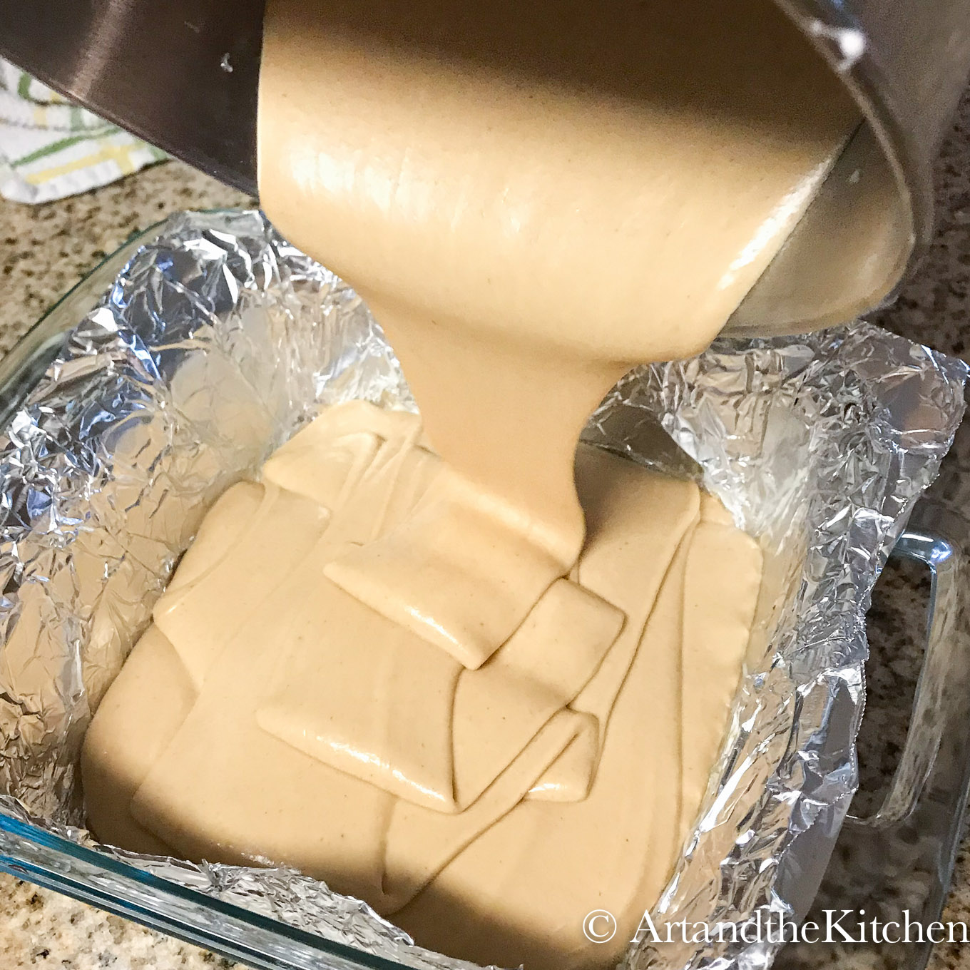 Pouring smooth peanut butter fudge into foil lined baking pan.