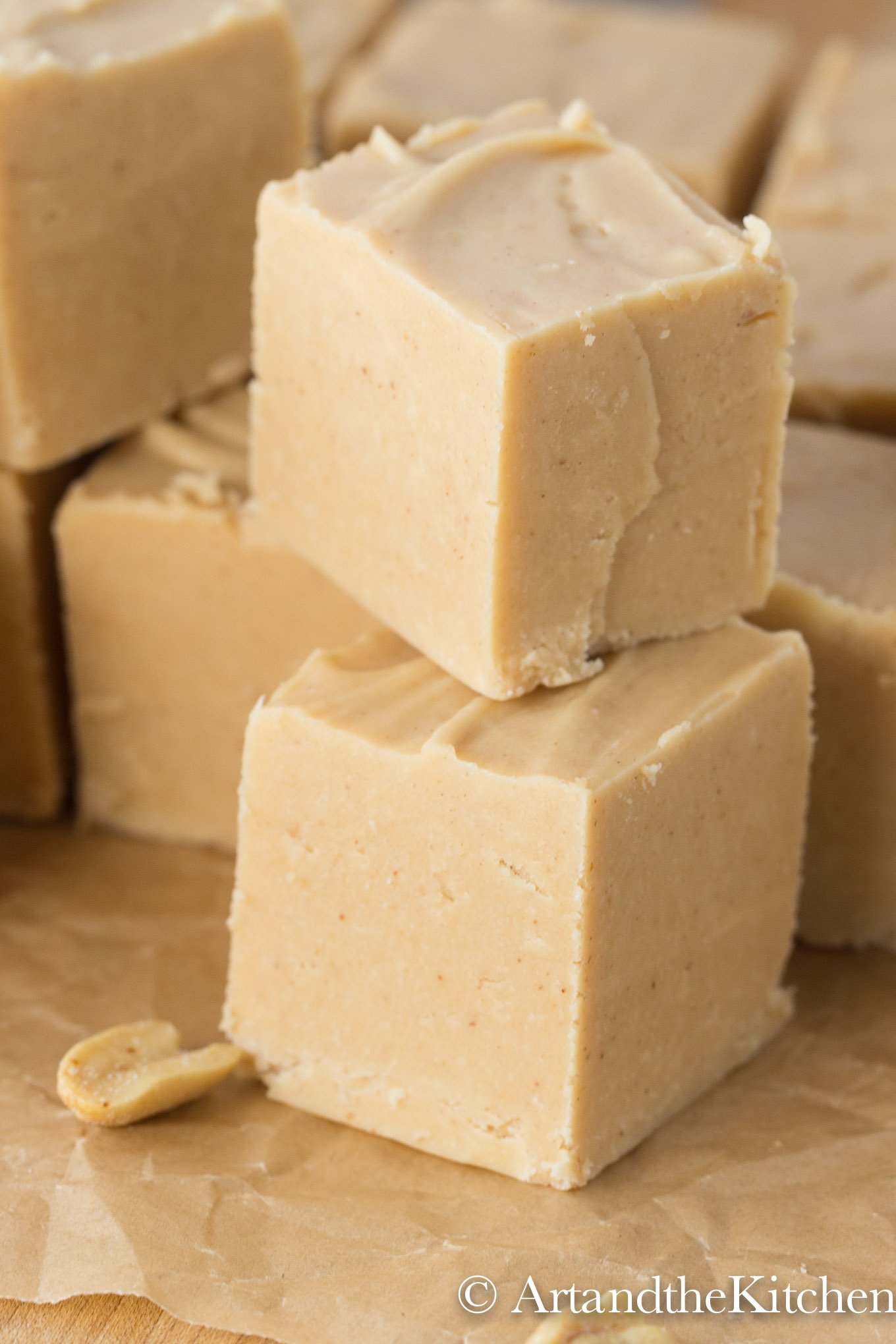 Stack of peanut butter fudge cubes on brown parchment paper.