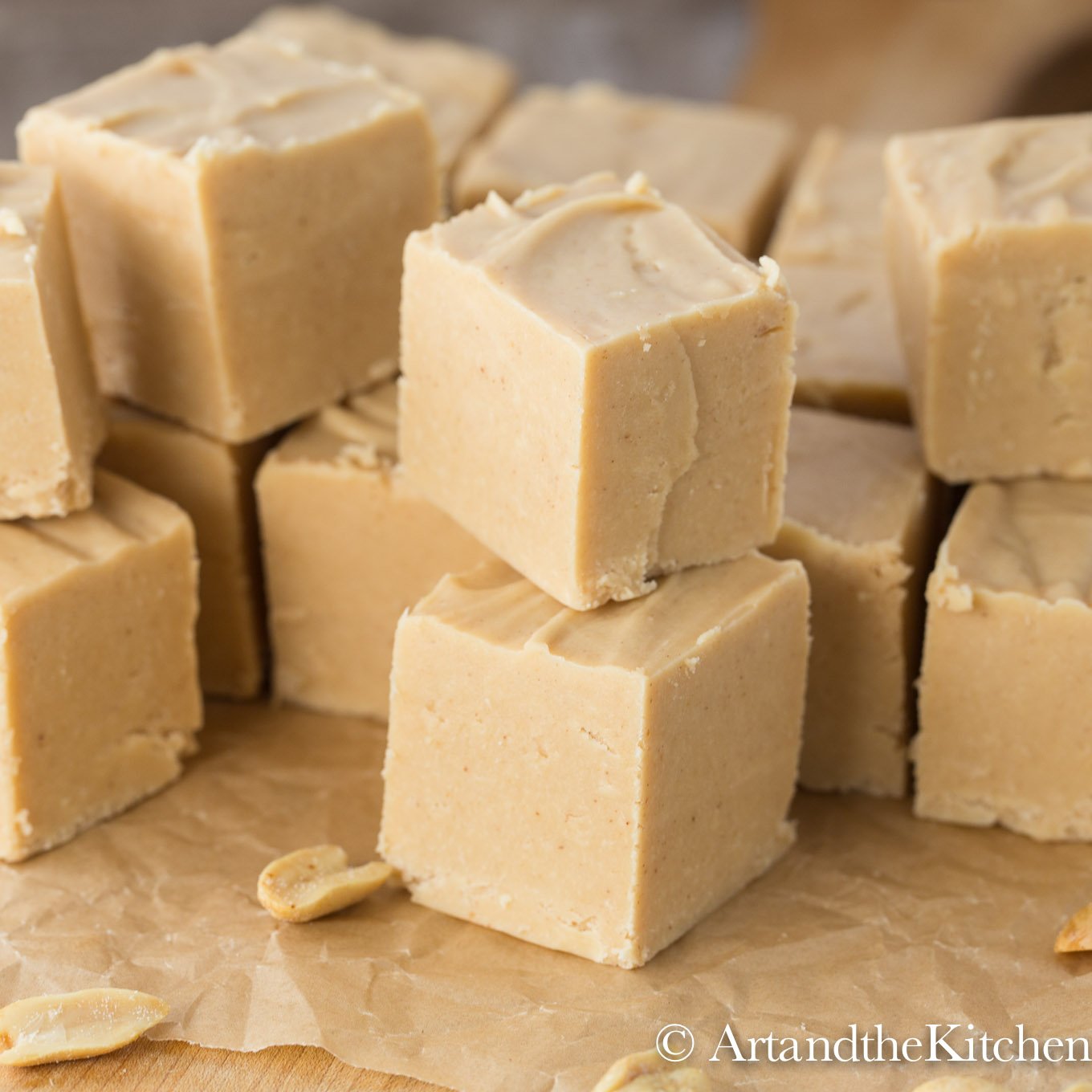 Stack of cubes of peanut butter fudge on brown parchment paper.