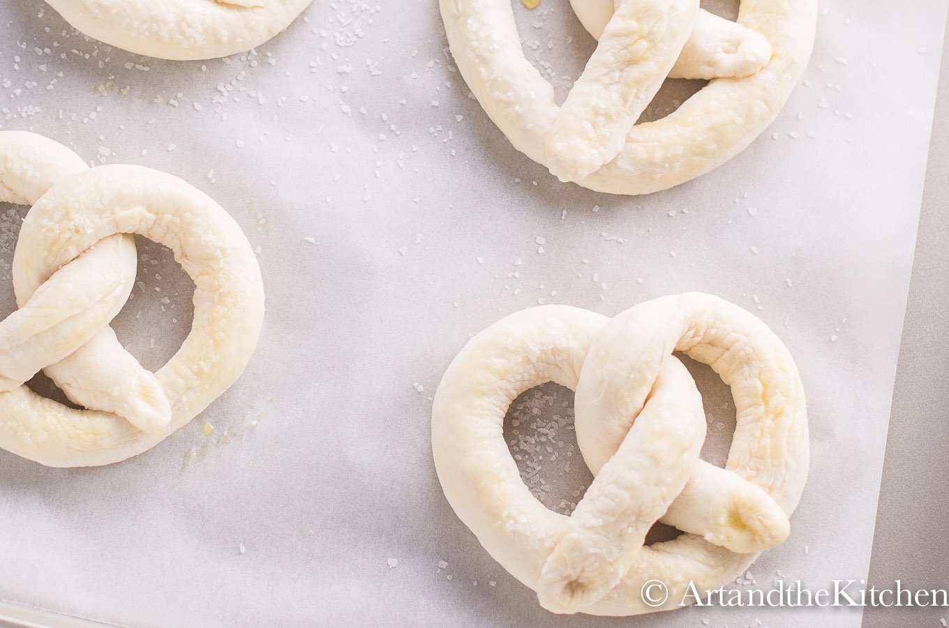 pretzel dough twisted into pretzel shaped on parchment paper