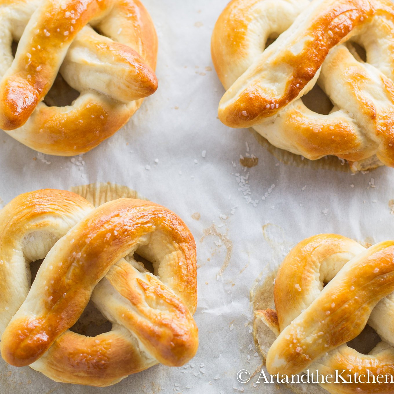 four homemade pretzels on parchment line baking sheet