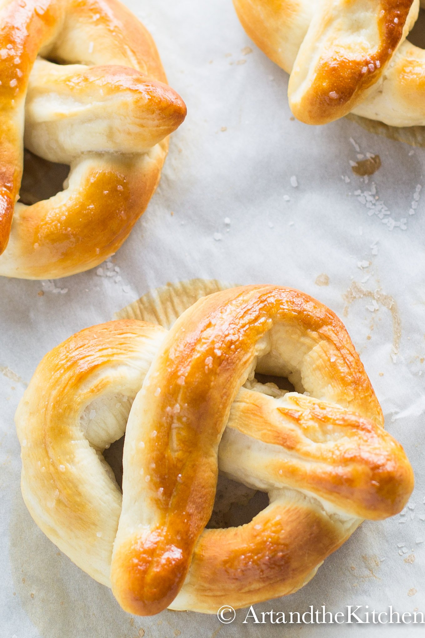 three homemade pretzels on parchment line baking sheet