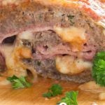 Meatloaf stuffed with ham and mozzarella cheese, garnished with parsley leaves.