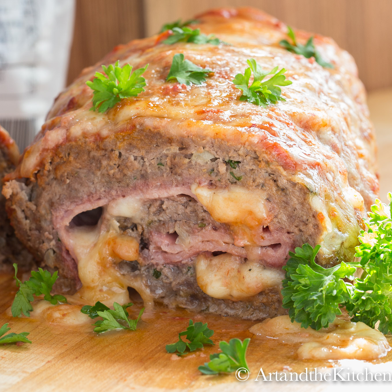 Meatloaf stuffed with ham and mozzarella cheese, garnished with parsley leaves.