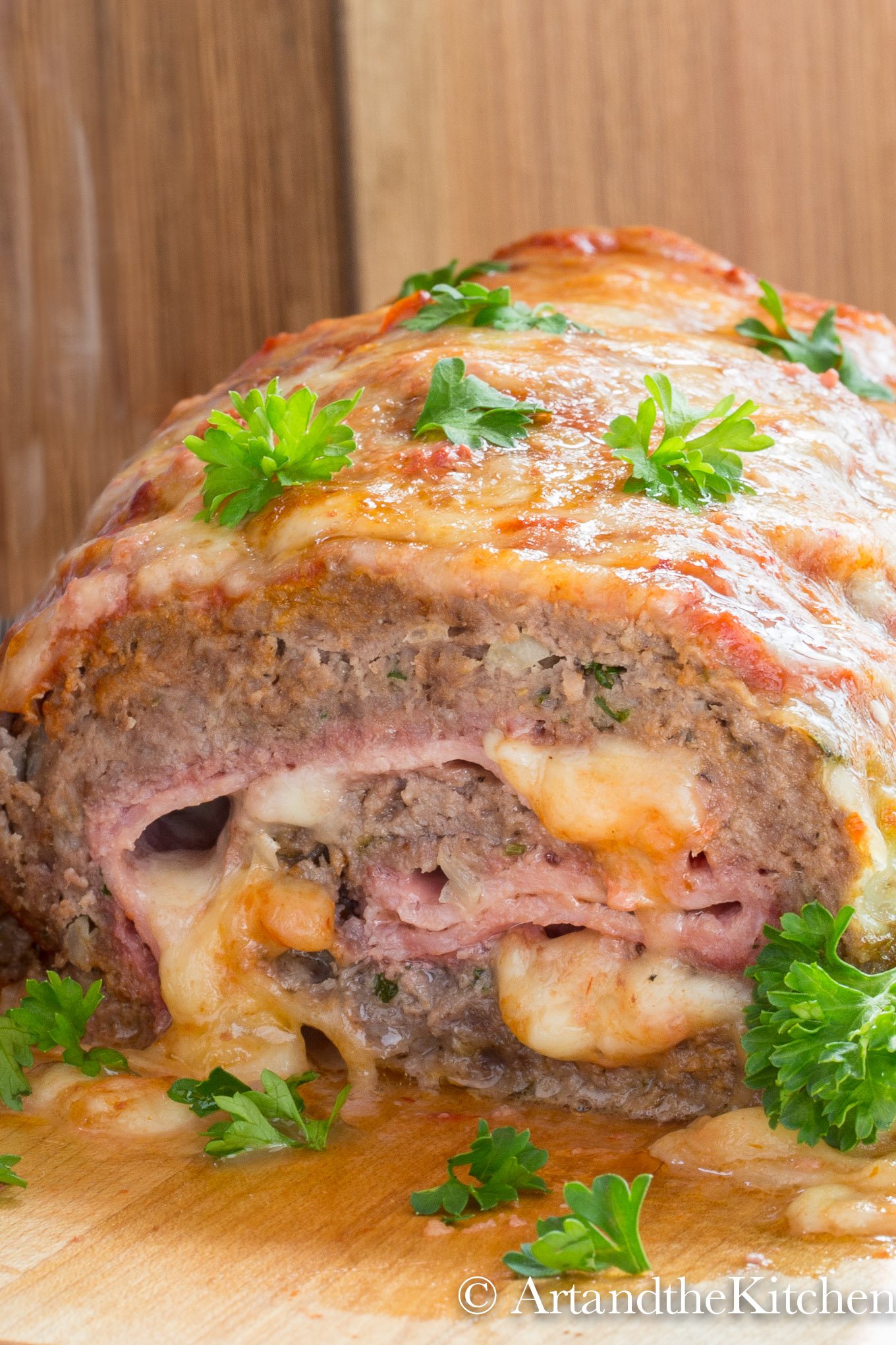 Meatloaf stuffed with ham and mozzarella cheese, garnished with parsley leaves.