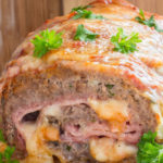 Meatloaf stuffed with ham and mozzarella cheese, garnished with parsley leaves.