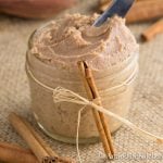 Small glass jar decorated with a ribbon and cinnamon stick, filled with cinnamon butter.