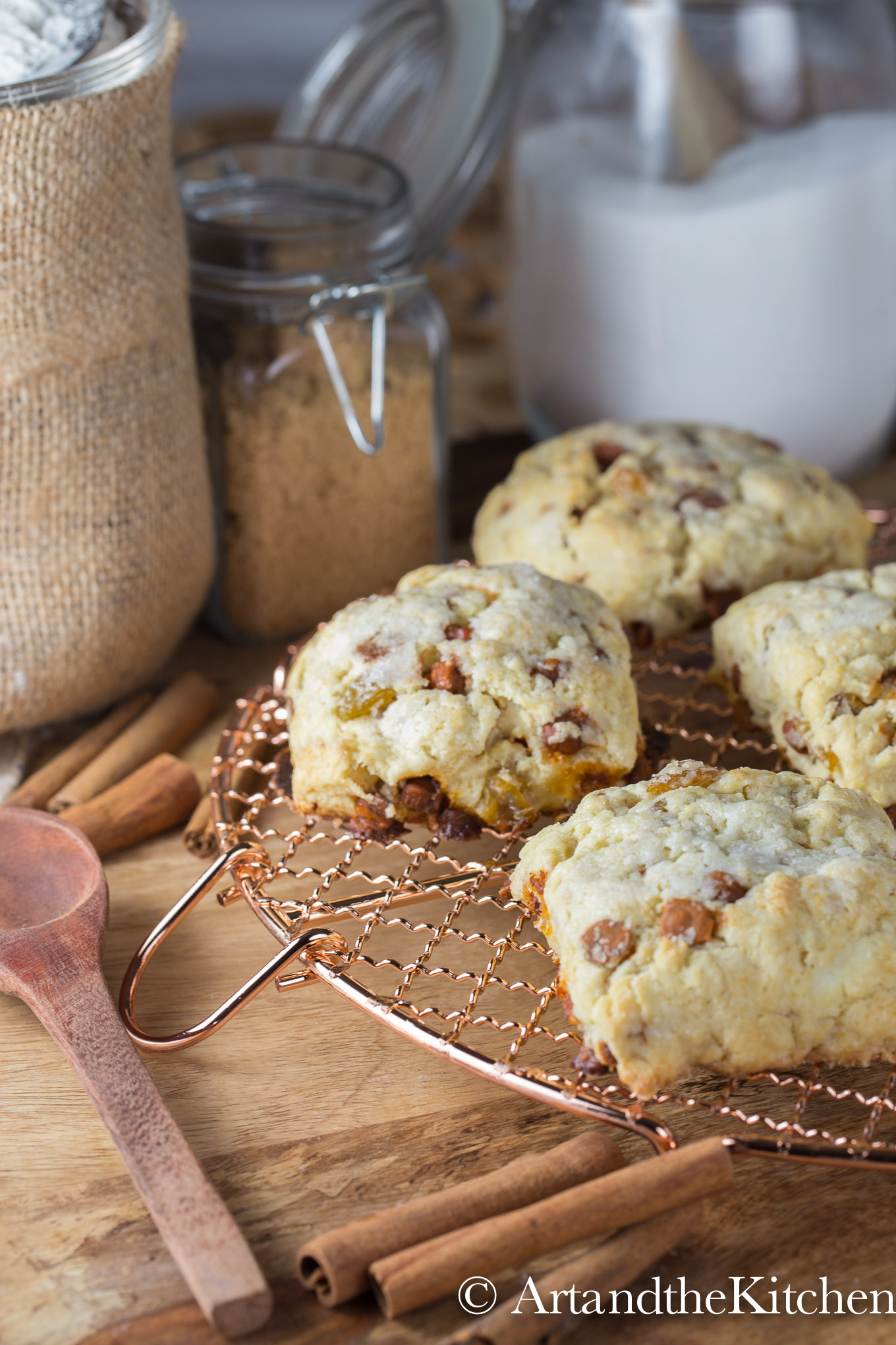 scones on a copper cooling rack with decorative jars of sugar in the background