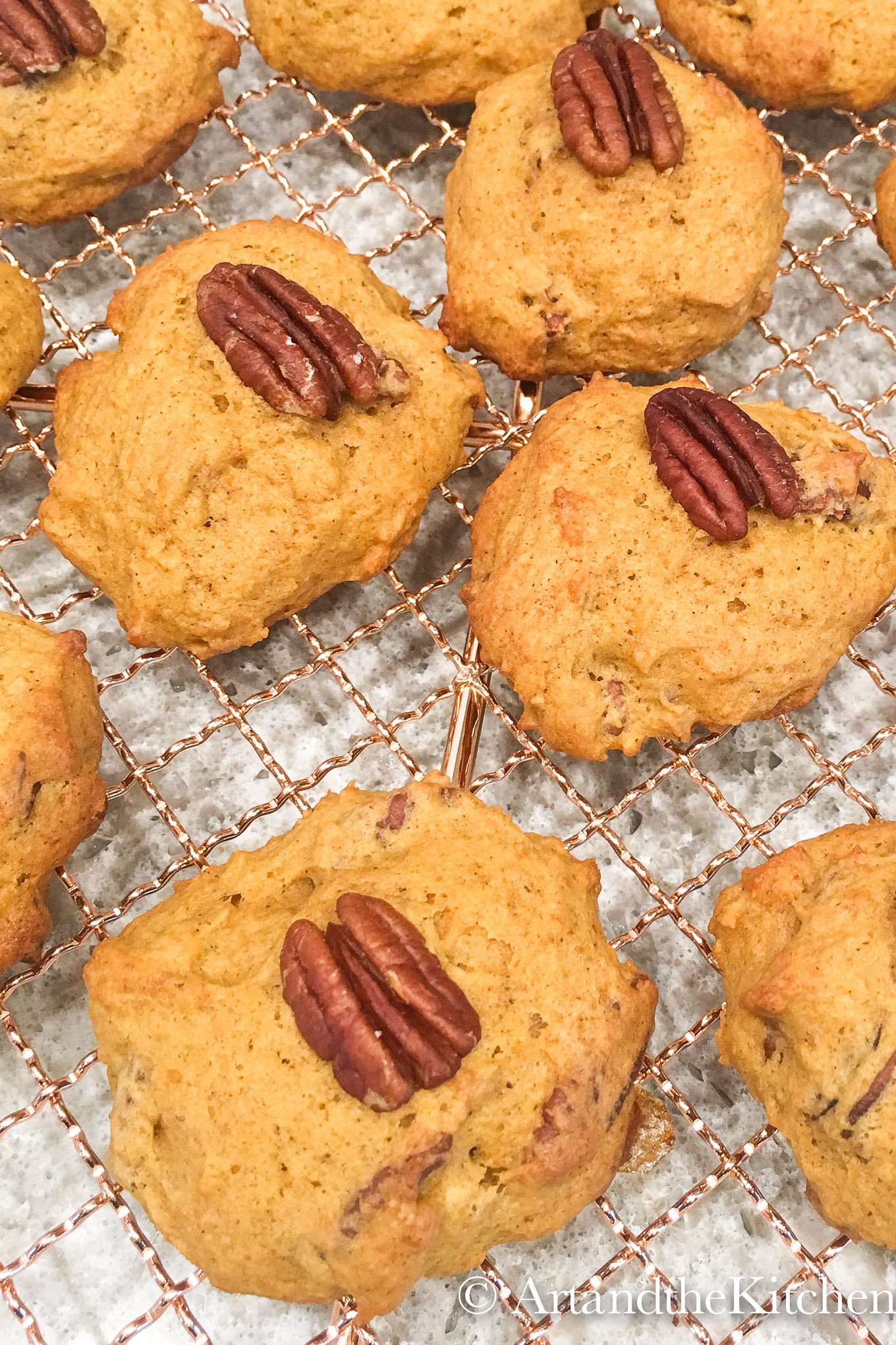 Wire rack filled with pumpkin cookies topped with a pecan.