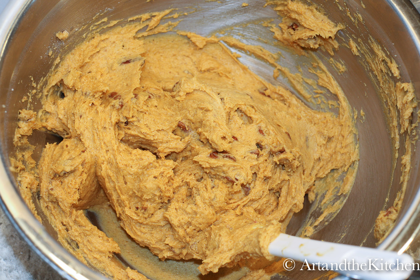 Stainless steel bowl filled with cookie dough for pumpkin cookies.