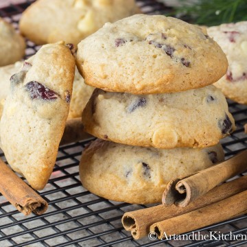 Stack of three puffy eggnog cookies with cranberries and side decoration of cinnamon sticks.