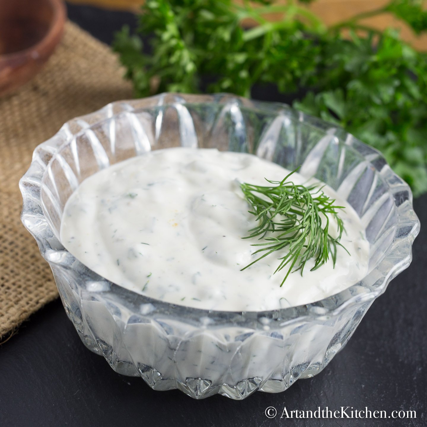 Glass bowl filled with dip, garnished with dill sprig.