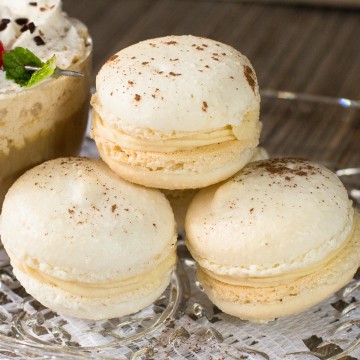 Stack of three Irish cream filled macaron cookies on glass plate.