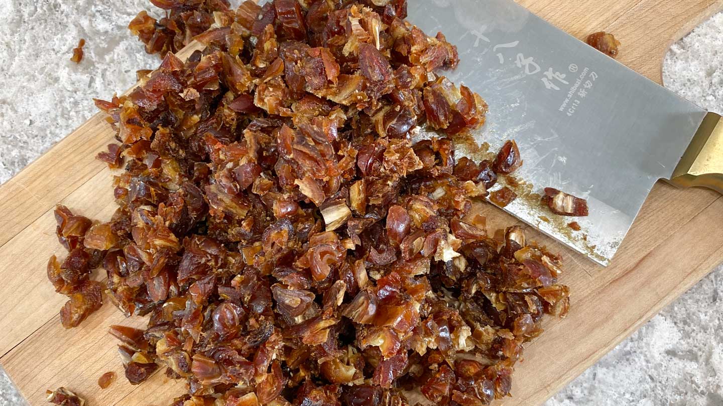 Chopped dates on wood cutting board.