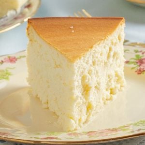 Slice of crustless, plain cheesecake on decorative plate.