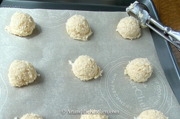 Scoops of cookies on parchment lined baking sheet.