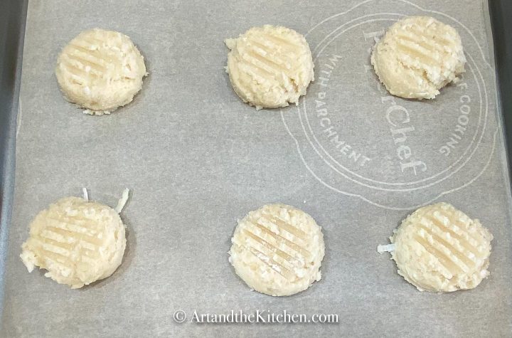 Parchment paper lined baking sheet filled with ready to bake sugar cookies