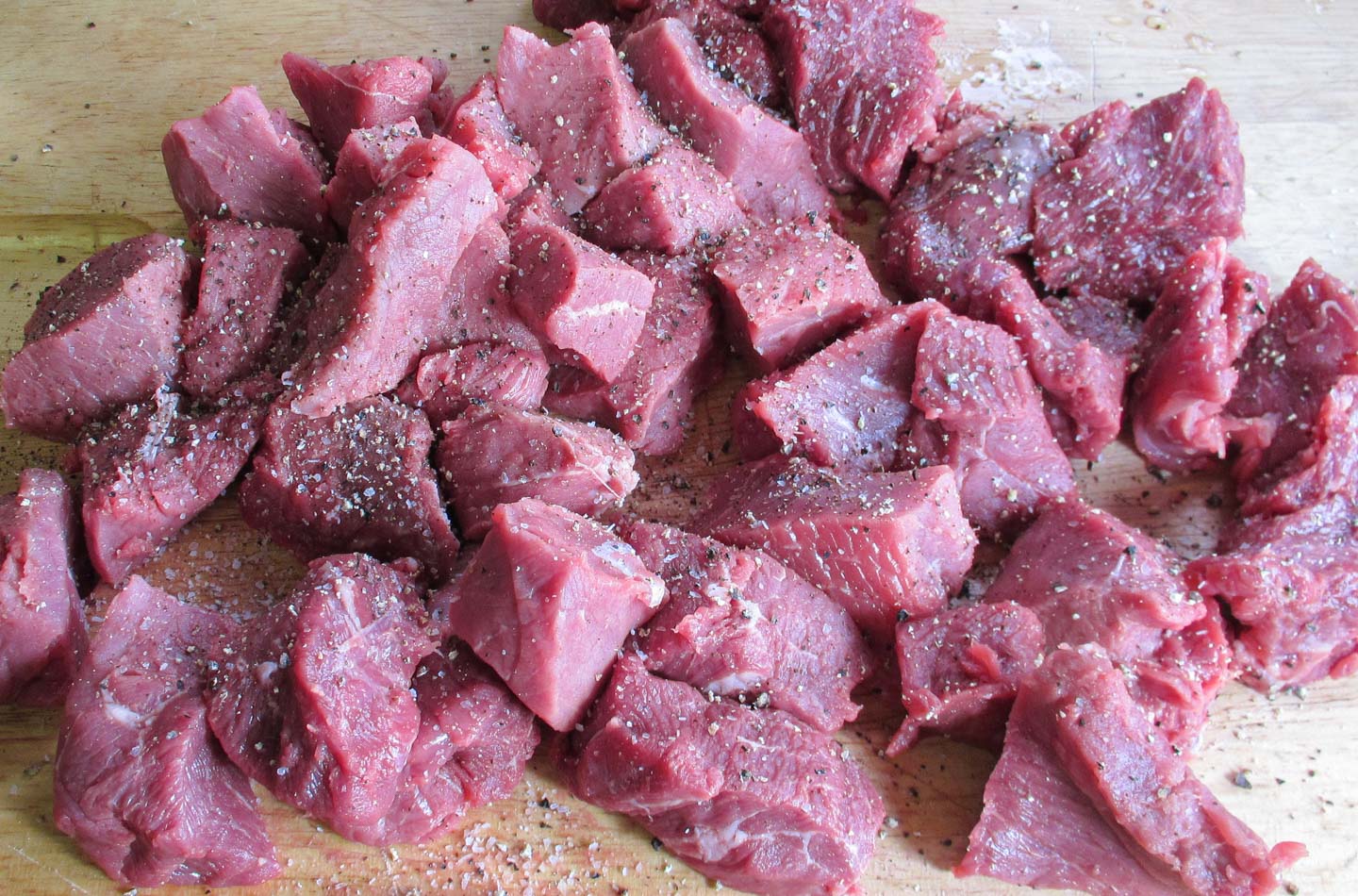 Cubes of raw beef seasoned with salt and pepper.