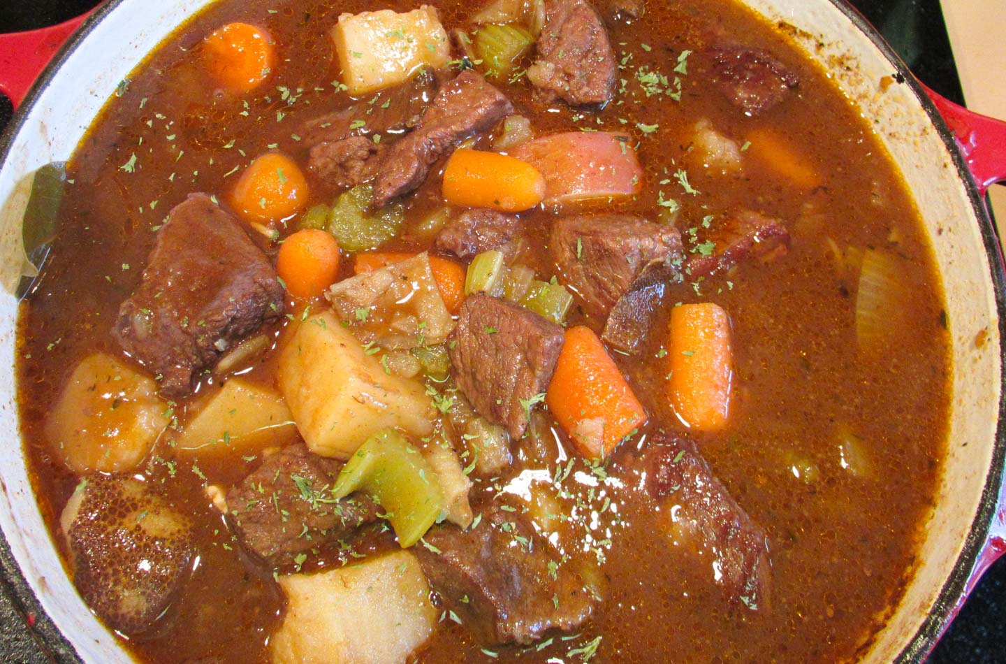 Pot of beef stew with potatoes, carrots and vegetables in rich gravy.